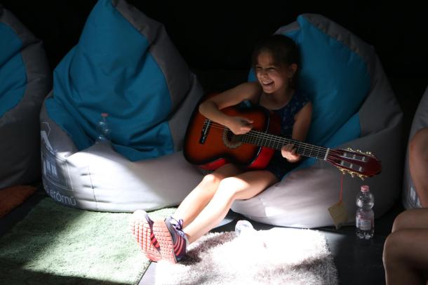 Az egyik kislány kipróbálja a gitárt.