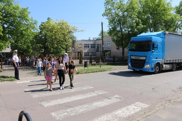 Rendőri kisérettel mennek át a zebrán a gyerekek.