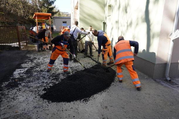 Kézi erővel terítik az aszfaltot a munkások.