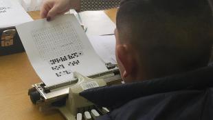 Braille írást tanulmányozza egy kisfiú.